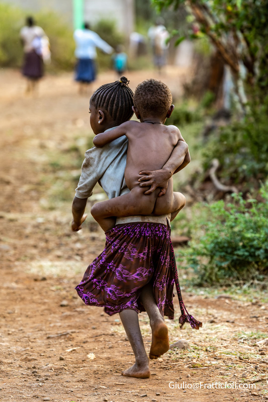 Bambina che corre con il fratellino in spalla